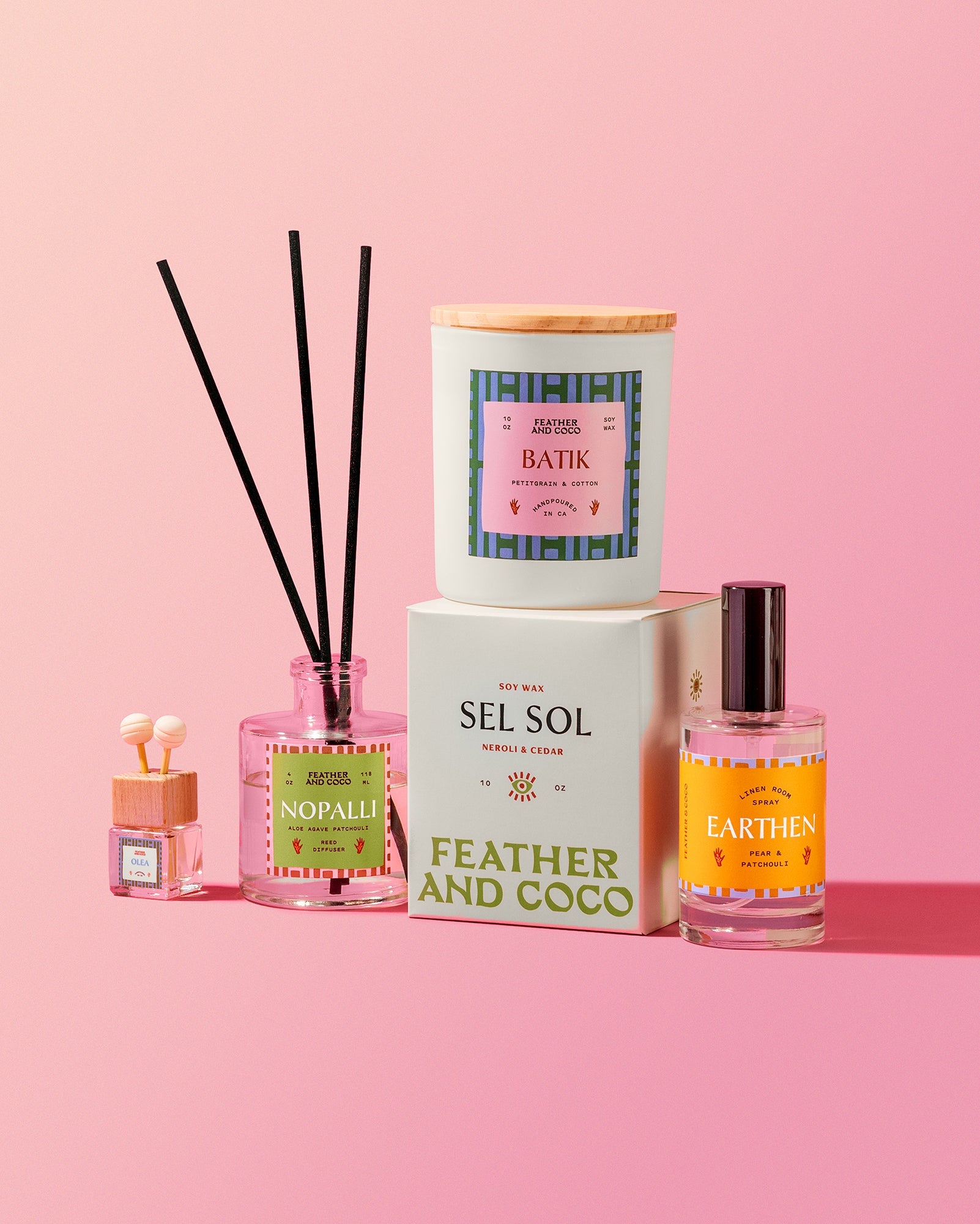 A collection of candles and diffusers on a pink background