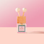 Batik Car Diffuser with wooden cap and pink label on a pink background