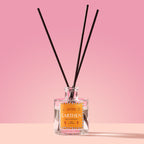 Earthen Reed Diffuser in a glass bottle on a pink background