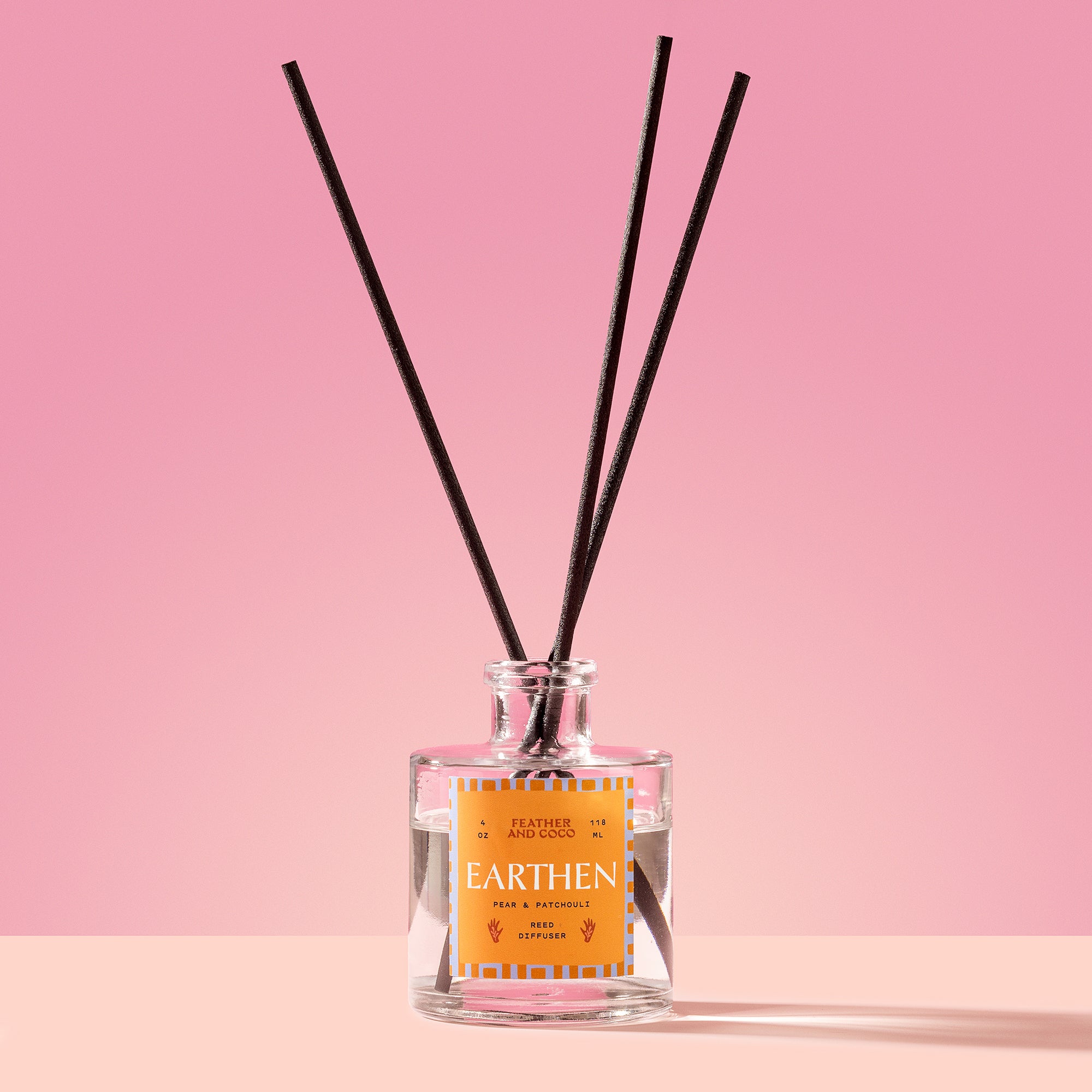 Earthen Reed Diffuser in a glass bottle on a pink background
