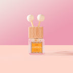 Earthen Car Diffuser with wooden cap and pink label on a pink background