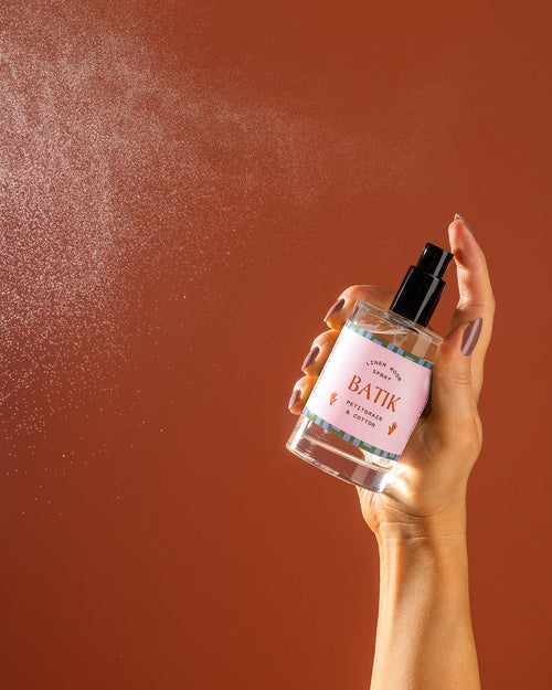 A bottle being sprayed against an orange backdrop.