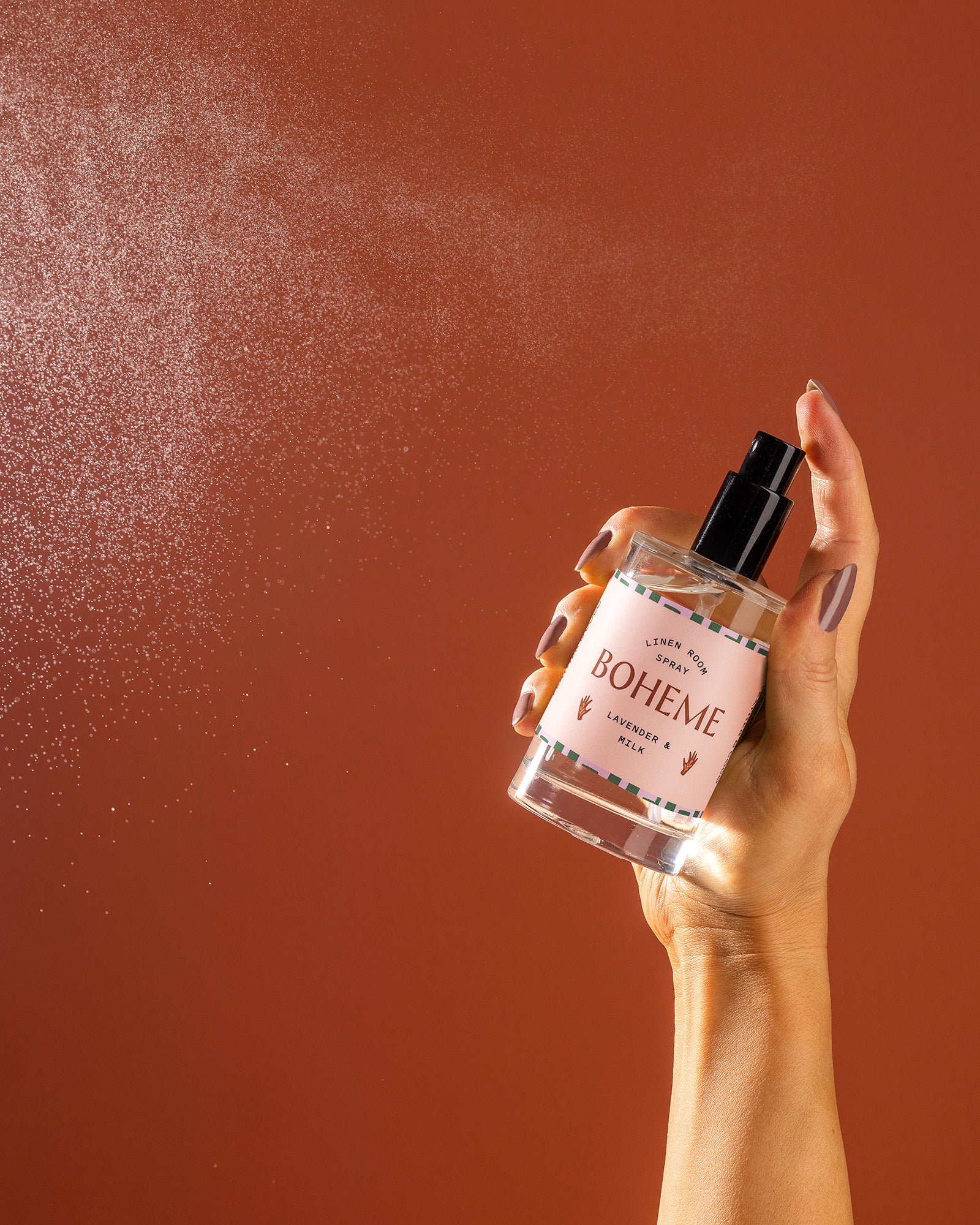 A bottle being spraying against an orange backdrop. 