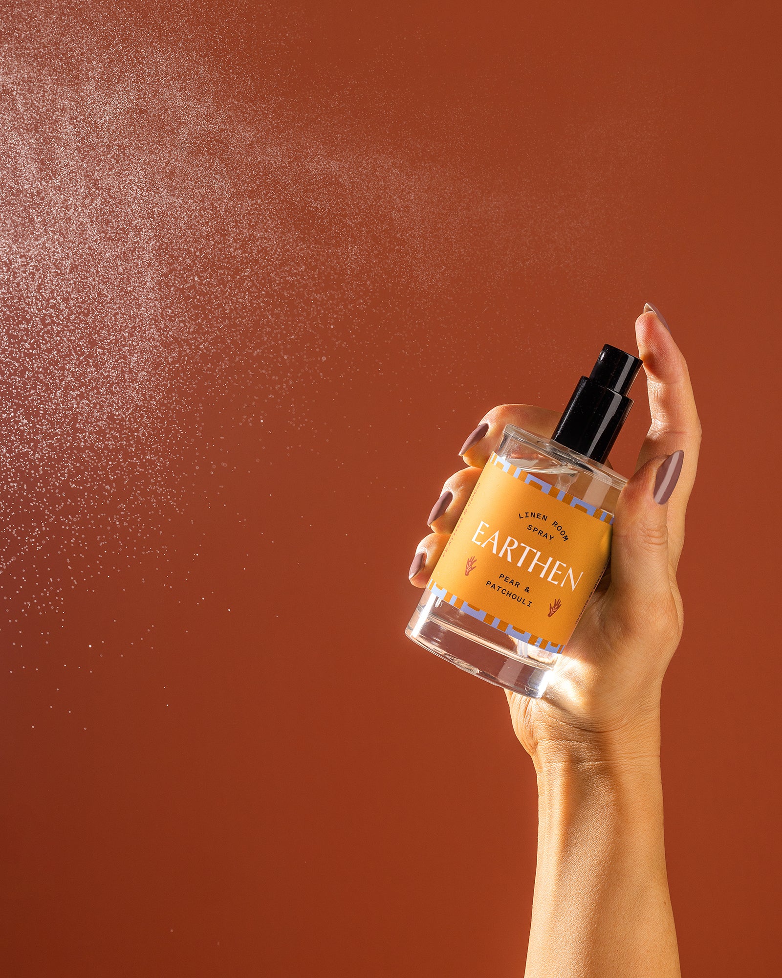 A bottle being sprayed against an orange backdrop. 