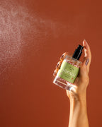 A bottle being sprayed against an orange backdrop.