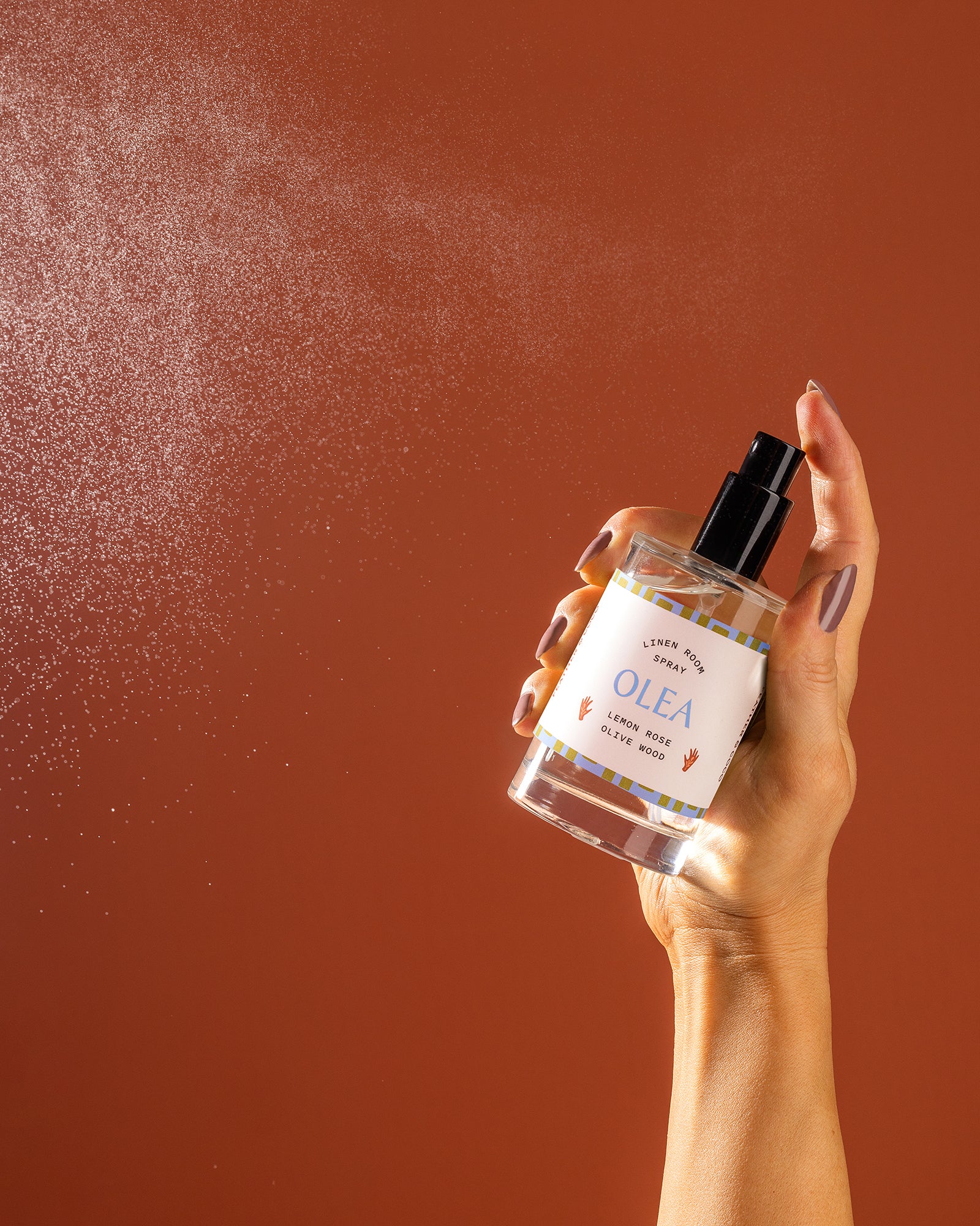 A bottle being sprayed against an orange backdrop. 