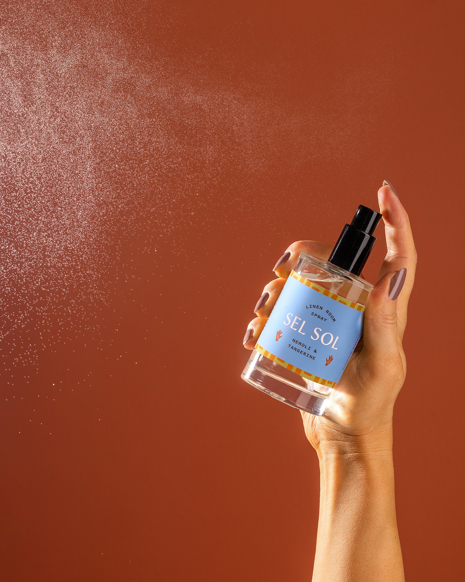 A bottle being sprayed against an orange backdrop. 