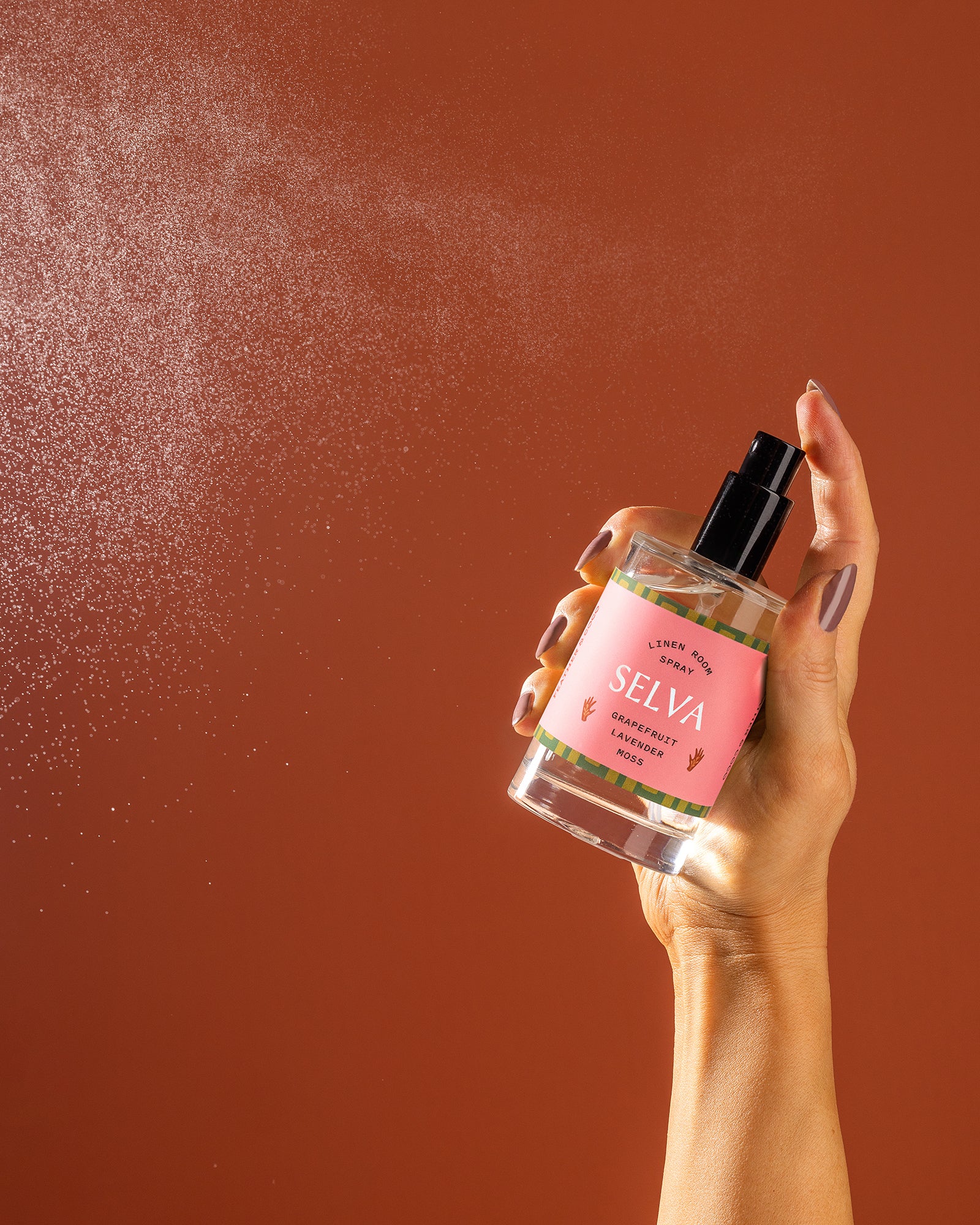 A bottle being sprayed on an orange backdrop. 