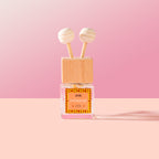 Nomad Car Diffuser with wooden cap and pink label on a pink background
