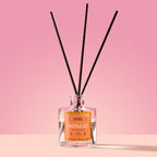 Nomad Reed Diffuser in a glass bottle on a pink background