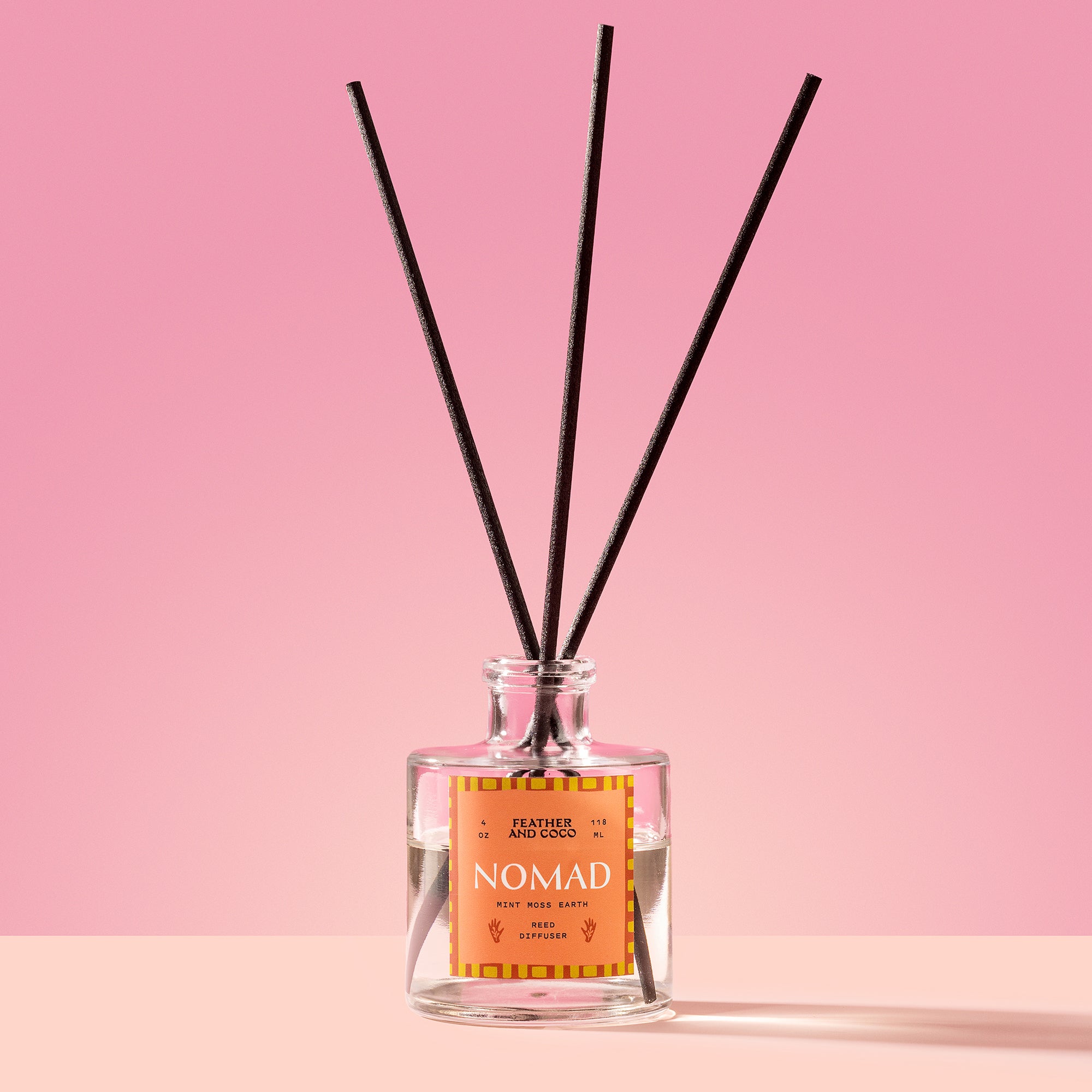 Nomad Reed Diffuser in a glass bottle on a pink background