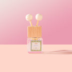 Olea Car Diffuser with wooden cap and pink label on a pink background