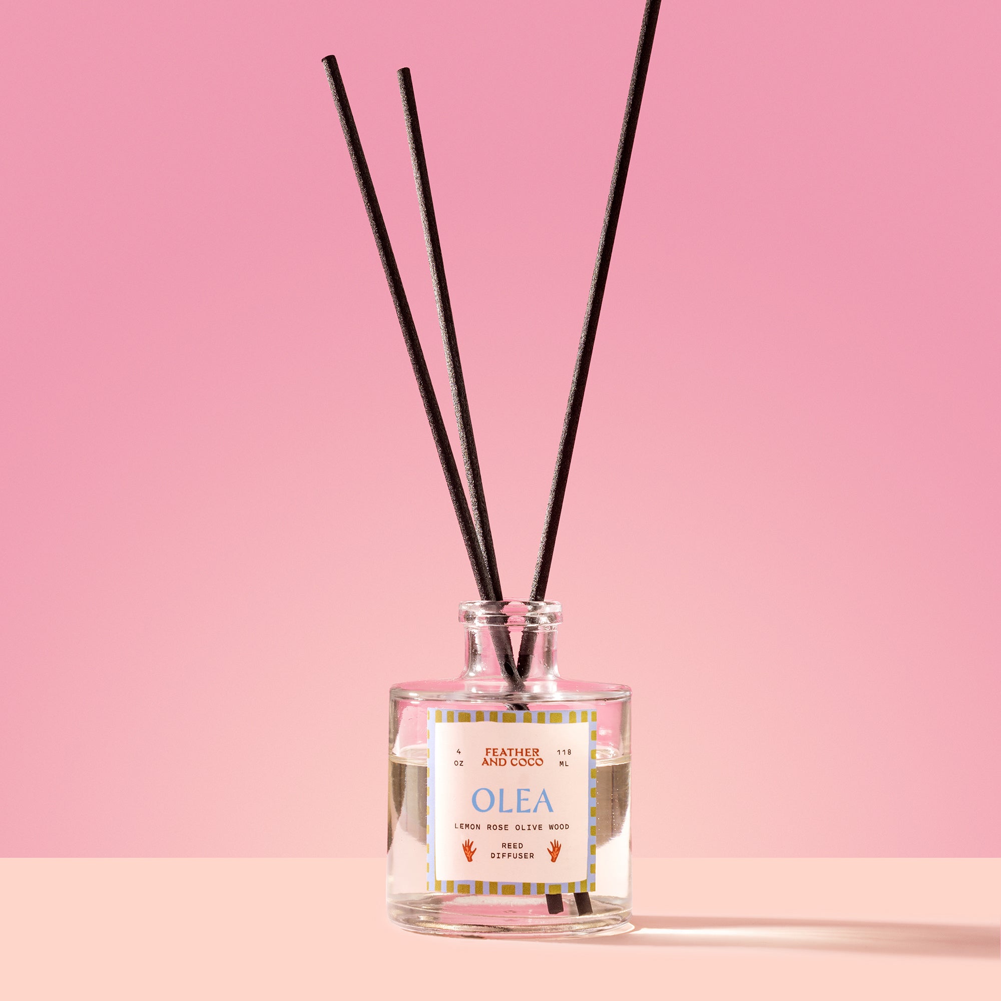 Olea Reed Diffuser in a glass bottle on a pink background